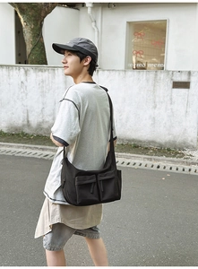 Detail of black nylon messenger bag with double front pockets and adjustable strap