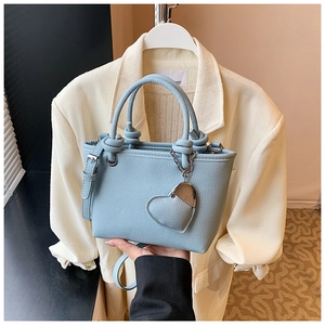 Macro shot of light blue lychee-textured bucket bag with silver heart charm and round handles