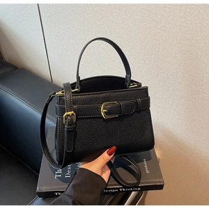 Détail d'un sac à main en cuir noir avec boucles dorées et bandoulière réglable