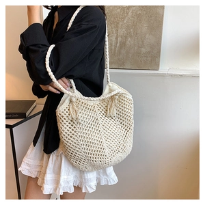 Detail of hand-woven cream tote bag showing hollow mesh texture and stylish tassel charm