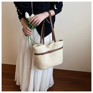 Detailed weave texture of off-white straw tote bag with brown leather strap detail