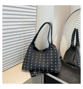 Detail of black pebbled leather tote bag with silver metal eyelets in lifestyle setting