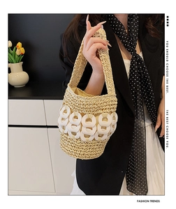 Detail of hand-woven beige straw bucket bag featuring modern white ring decorations