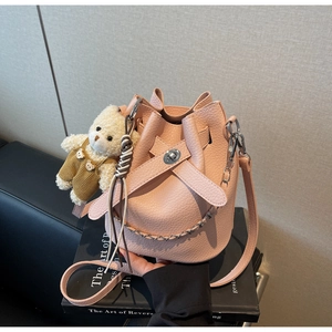 Detailed macro of pink litchi grain leather bucket bag with cute teddy bear charm