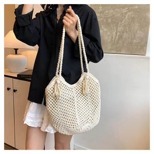 Bohemian style cream woven tote bag with fringe tassels and braided shoulder strap on model