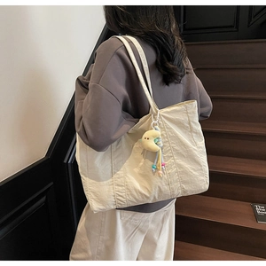 Detail of off-white large capacity tote bag with yellow moon charm on a shoulder strap