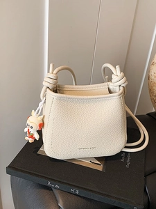 Minimalist beige pebble leather bucket bag with top handle and cute rabbit charm