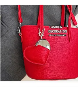 Close-up of red pebble leather bucket bag with silver chain and heart charm detail