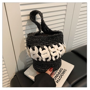 Detail of hand-woven black straw bucket bag with white linked ring chain decor