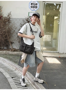 Detail of a black multi-pocket utility crossbody bag paired with street style outfit