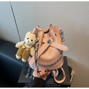 Detailed close-up of pink lychee grain bucket bag with metal lock and cute bear charm
