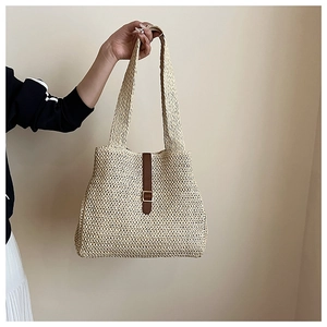 Détail du sac cabas en paille tissée à la main avec sangle en cuir marron et boucle dorée