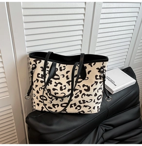 Dettaglio della borsa tote in tela leopardata con manici in pelle nera su seduta