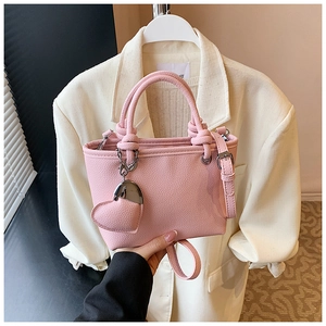 Detailed macro view of pink lychee grain leather bucket bag with knotted handle and heart charm