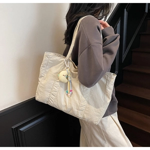Detailed view of cream nylon tote bag with plush moon charm and embroidery