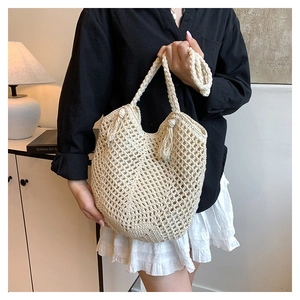 Detail of hand-woven cream tote bag with bohemian tassels and hollow mesh design