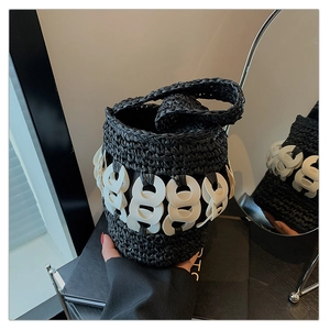 Detail of hand-woven black straw bucket bag with white acrylic ring chain accents