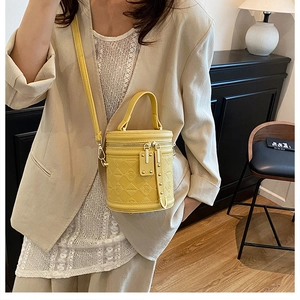 Detail of yellow quilted cylinder bucket bag with bear logo and metal zipper closure