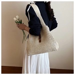 Vue latérale détaillée d'un grand sac cabas en paille avec boucle en cuir marron et sangle