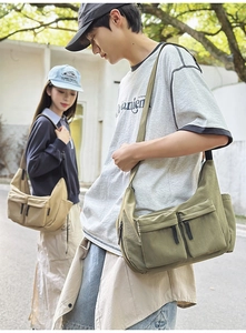 Detail view of khaki and olive canvas messenger bags with multiple functional zipper pockets