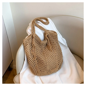 Close-up of the hollowed-out knit texture and long side tassels on the woven tote bag
