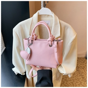 Pink lychee textured bucket bag featuring a knot handle and heart charm detail