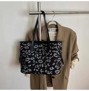 Dettaglio della grande borsa tote nera con stampa leopardata e anelli metallici