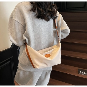 Detail of a minimalist beige oxford dumpling bag showing the texture and brown leather strap