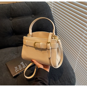 Gros plan détaillé du sac beige en cuir grainé avec boucle dorée élégante et texture