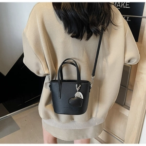 Close-up of black lychee texture bucket bag with heart pendant and adjustable strap