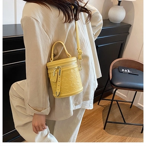 Close-up of bright yellow bucket bag with quilted patterns and stylish tassel detail