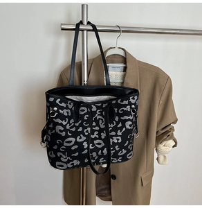 Dettaglio borsa shopper nera con trama leopardata grigia e anelli in metallo argento