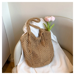 Detail of hand-woven mesh texture on beige tote bag with decorative tassel and tulip