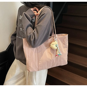 Pink nylon tote bag detail with TaoCal logo and yellow moon plush charm accessory