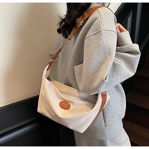 Detail of fashion Oxford fabric crossbody bag showing leather tag and wide shoulder strap