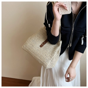 Détail du sac fourre-tout en paille tissé avec lanière en cuir brun et boucle en métal