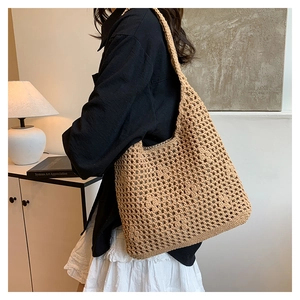 Detail of hand-woven beige bucket bag showing intricate cutout texture and sturdy shoulder strap