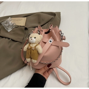 Detailed shot of pink lychee leather bucket bag with silver chain and teddy bear charm