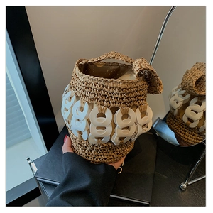 Detail of woven straw bucket bag with oversized white resin chain rings and top handle