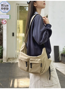 Outdoor shot of a khaki nylon crossbody bag with multi-pocket utilitarian design