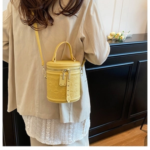Detail of yellow bucket bag featuring quilted rhombic patterns and silver hardware