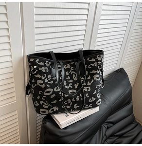 Dettaglio della grande borsa tote nera con motivo leopardato astratto argento e zip