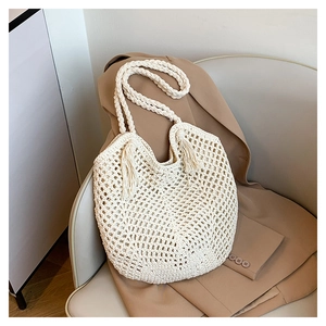 Detail of off-white crochet tote bag featuring hollow mesh texture and stylish dual tassels