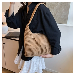 Close-up of beige hollow out woven beach bucket bag with textured crochet shoulder strap