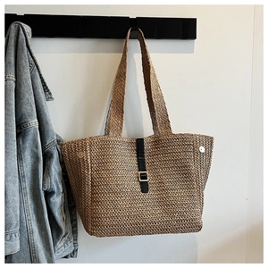 Détail d'un sac cabas en paille tressée avec bande en cuir noir et fermoir magnétique doré