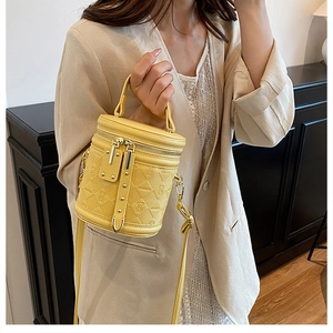 Detail of yellow quilted leather bucket bag with embossed bear pattern and gold zippers