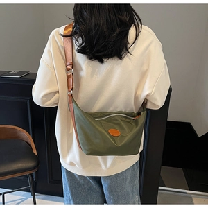 Olive green nylon dumpling bag with brown leather strap and silver zipper detail