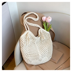 Detail of crochet woven tote bag featuring decorative tassels and hollow knit texture