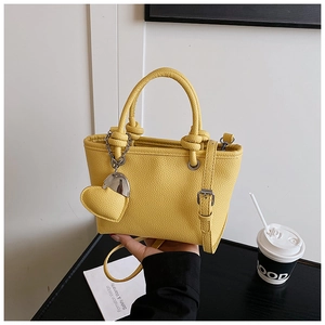 Detail of yellow lychee grain bucket bag with heart charm and detachable shoulder strap