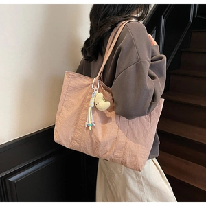 Detailed view of large peach tote bag with plush moon charm and woven tassel accent